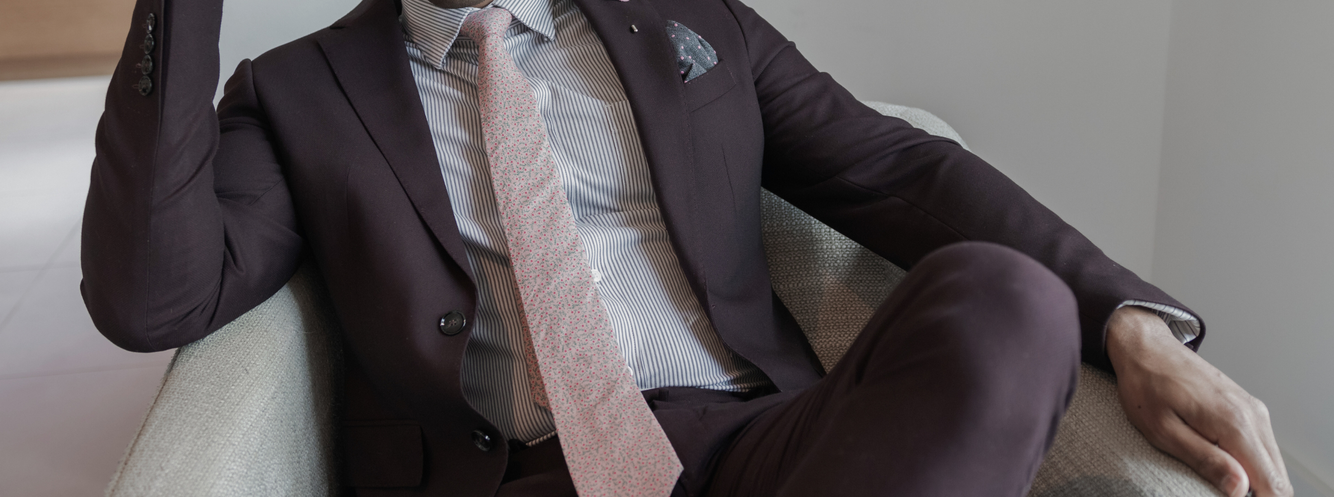 a gentleman sitting down in a burgundy suit