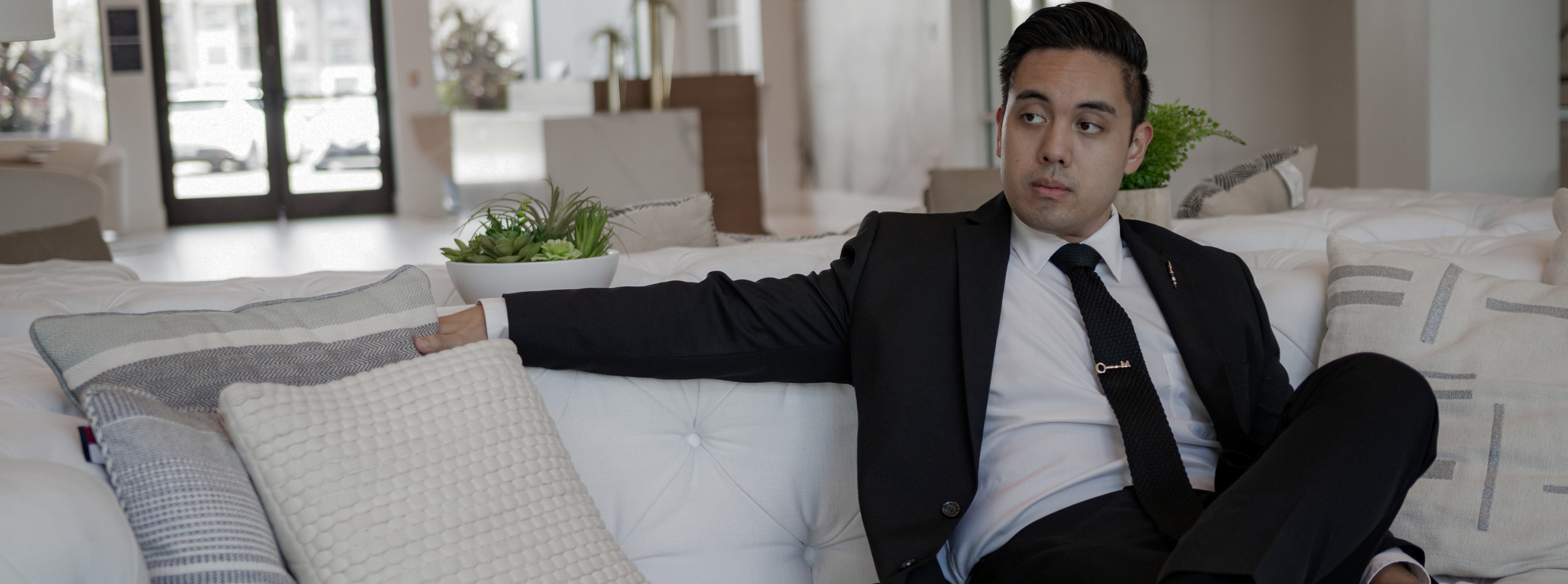 A gentleman sitting on a couch in a black suit