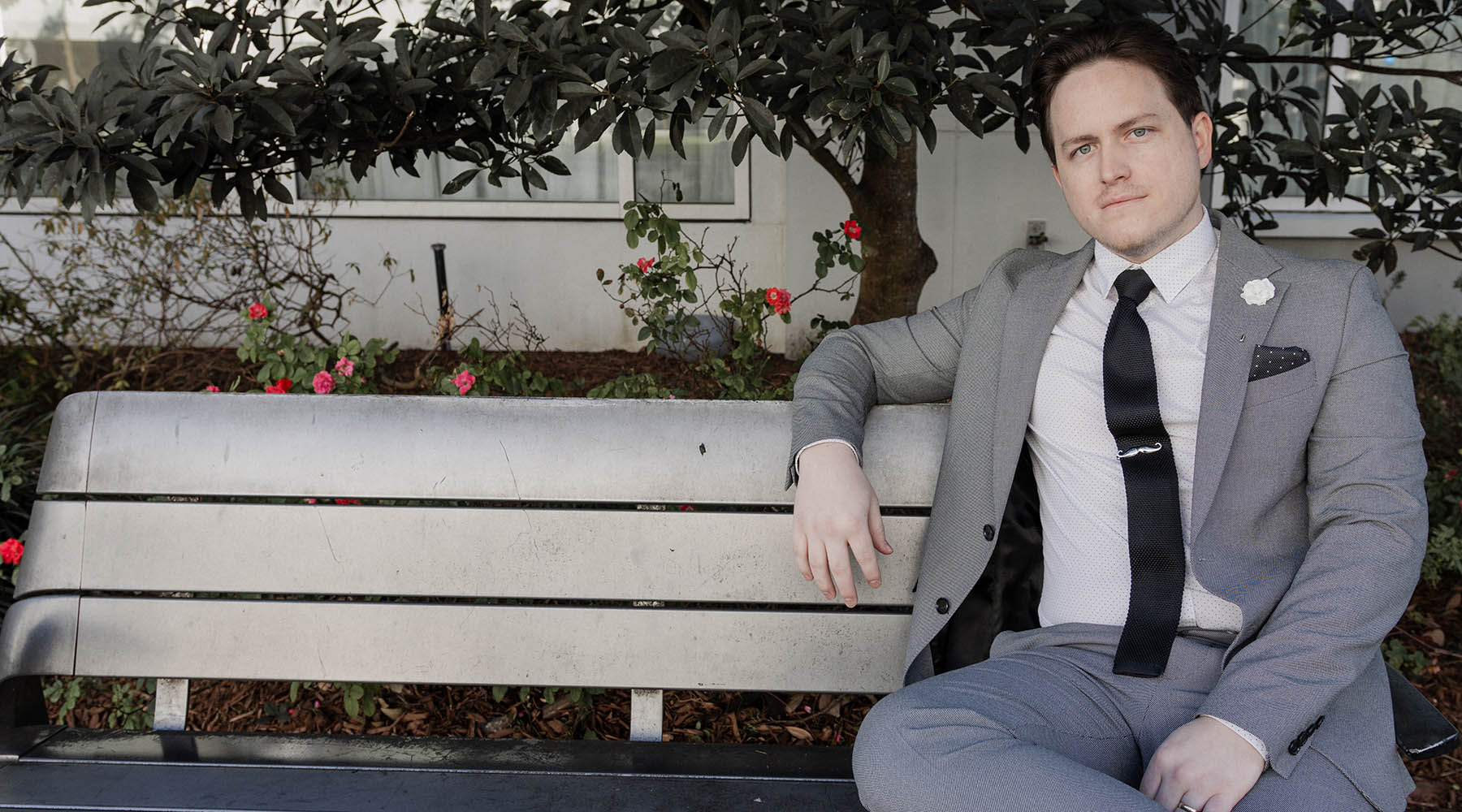 Man sitting on bench wearing a suit and knitted tie